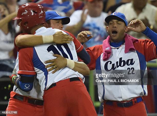 Cuba National baseball team's Yulieski Gurriel gets a hug from teammate Frank Camilo Morejon as Yadiel Hernandez waits his turn after scoring 3-1 on...