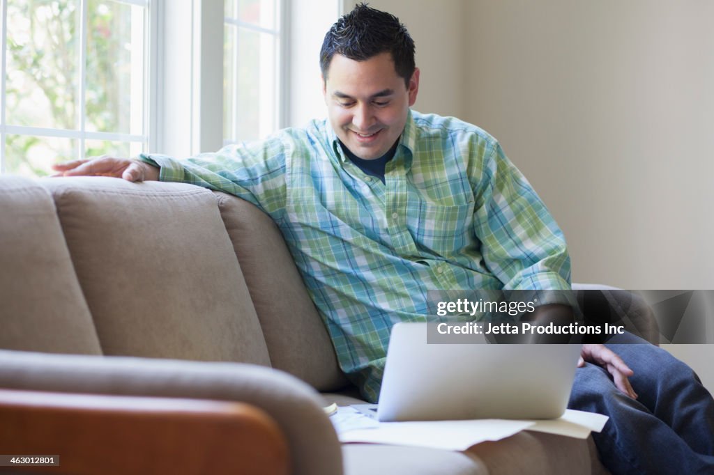 Pacific Islander man using laptop on sofa