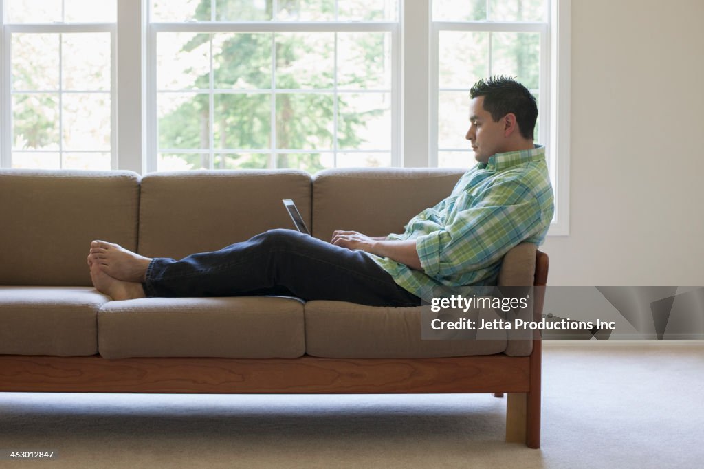 Pacific Islander man using laptop on sofa