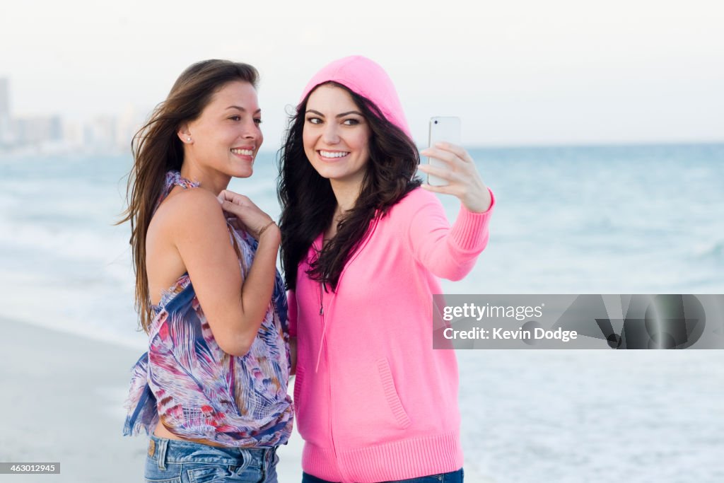 Women taking pictures together on beach
