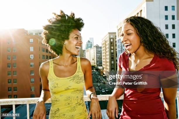 mixed race women smiling on urban rooftop - black female friends stockfoto's en -beelden