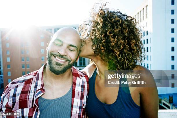 couple kissing on urban rooftop - black men kissing white women stock-fotos und bilder