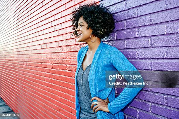 mixed race woman standing by colorful wall - bovenlichaam stockfoto's en -beelden