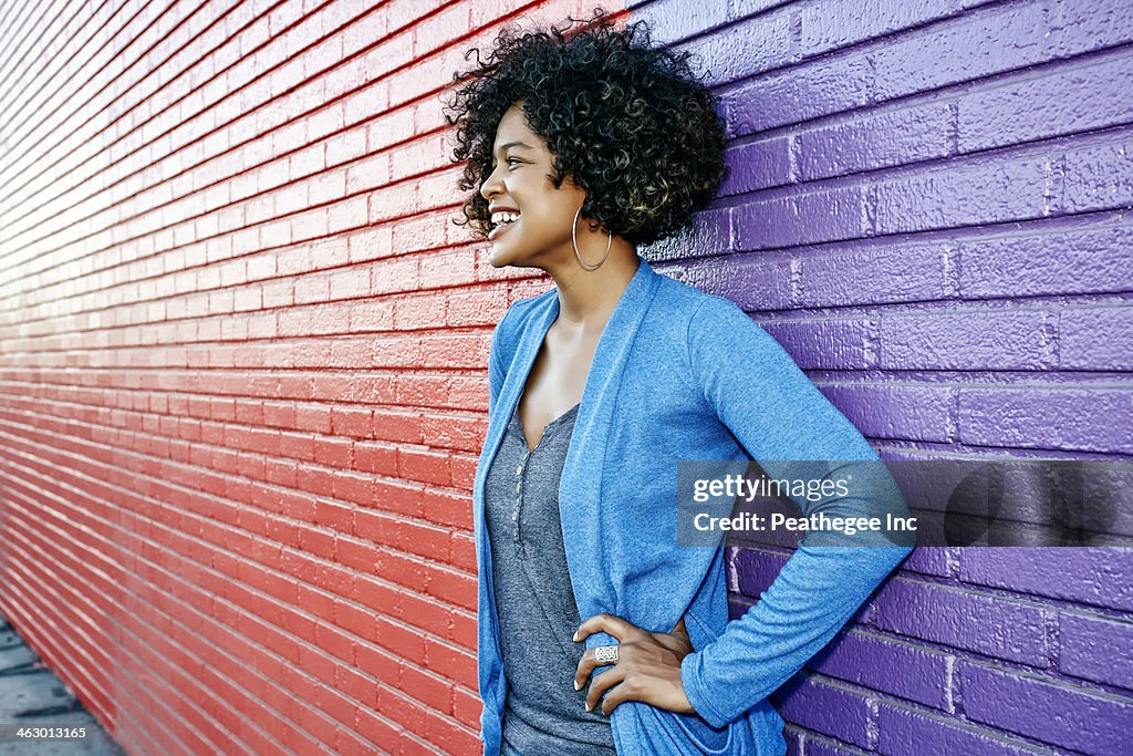 Mixed race woman standing by colorful wall