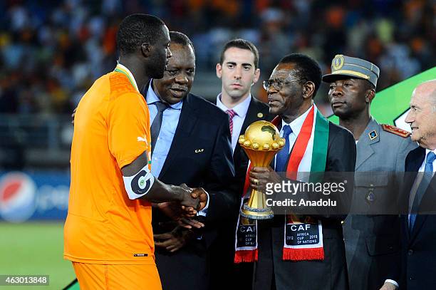 President Sepp Blatter looks on as Ivory Coast's Yaya Toure receives the trophy from Equatorial Guinea President Teodoro Obiang Nguema at the end of...