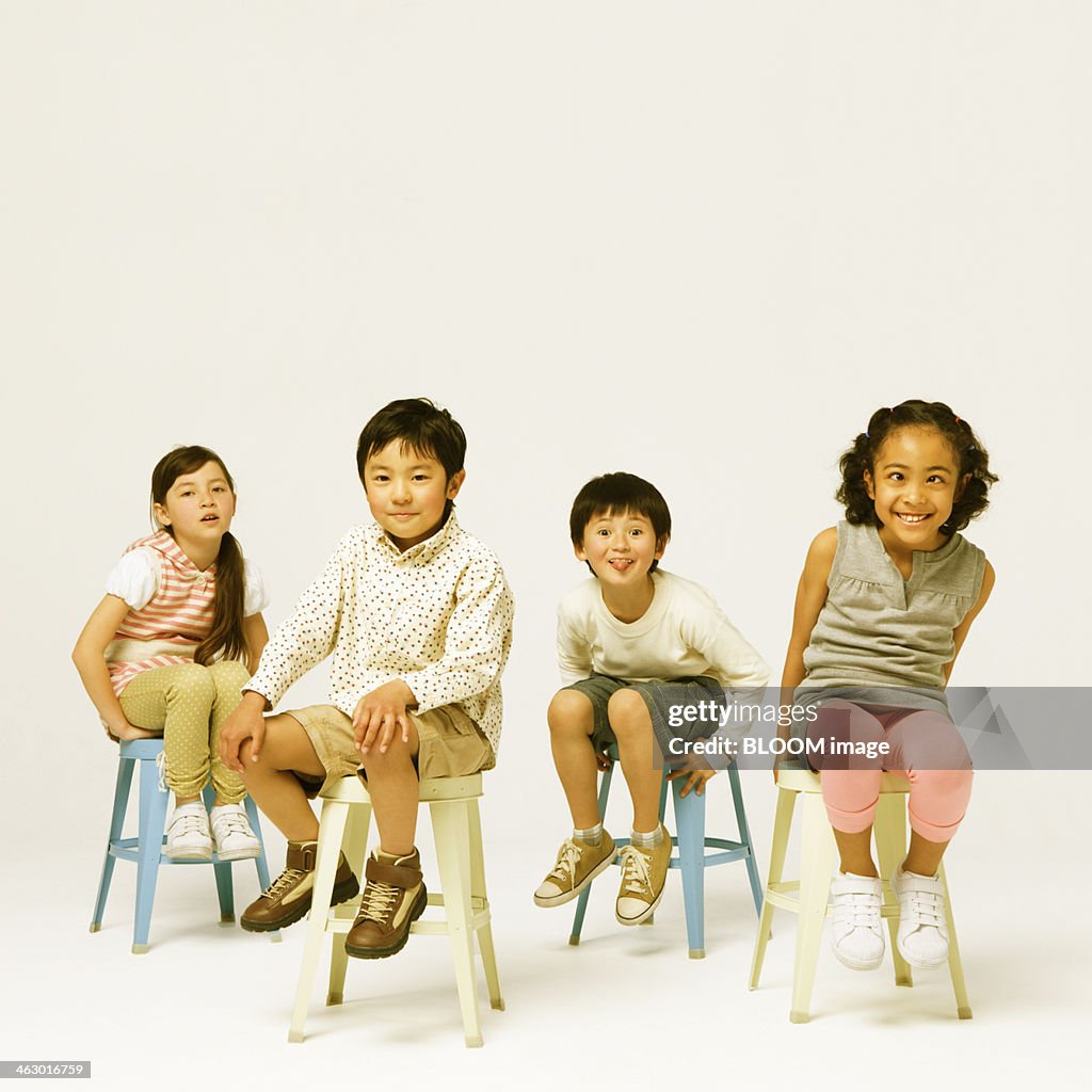 Group Of Children Sitting On Stool