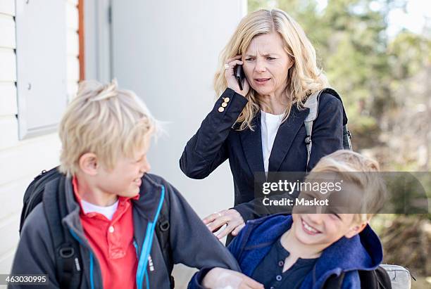 irritated mother using mobile phone while stopping mischievous sons - busy mother stock pictures, royalty-free photos & images