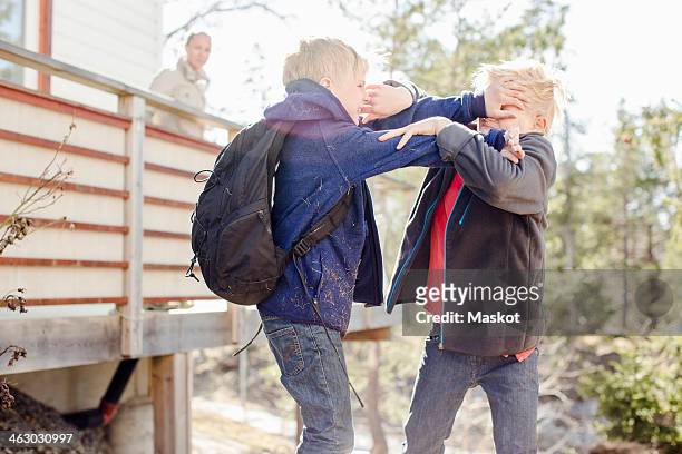 brothers fighting while mother looking at them from balcony - boys wrestling stockfoto's en -beelden