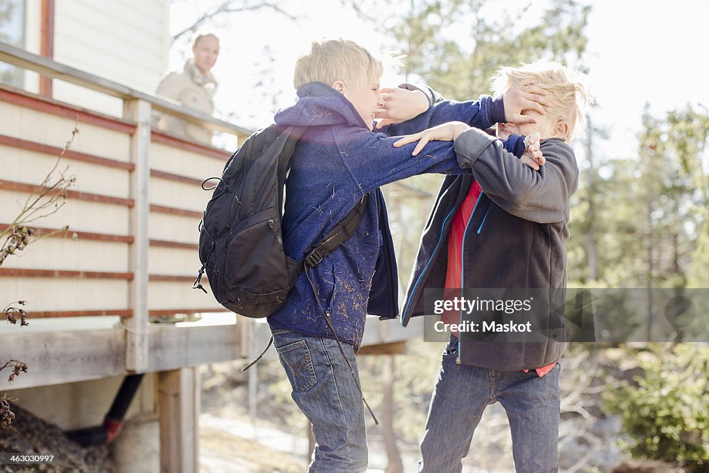 Brothers fighting while mother looking at them from balcony