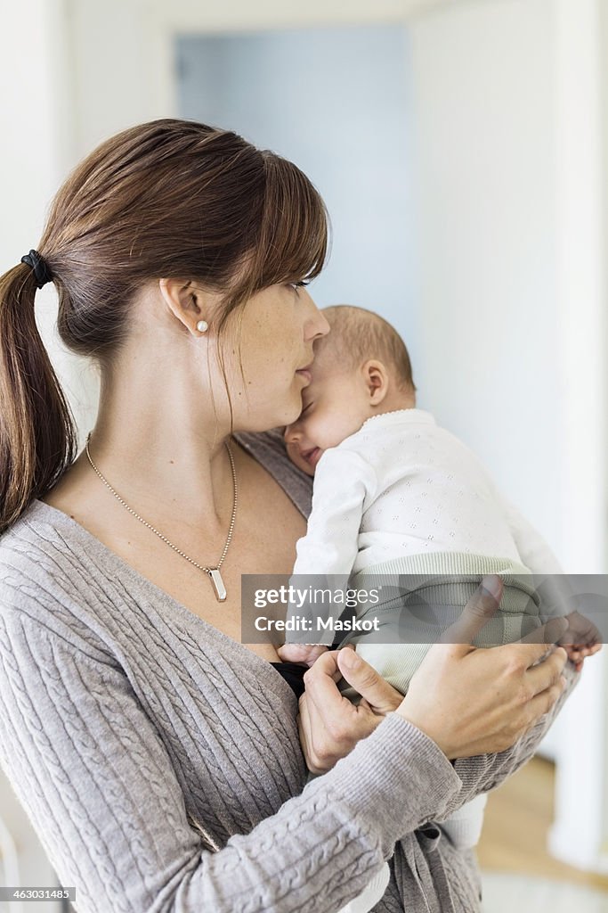 Mid adult woman carrying baby girl at home