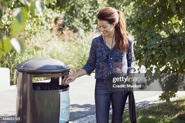 businesswoman throwing garbage in bin at park - throwing phone stock pictures, royalty-free photos & images