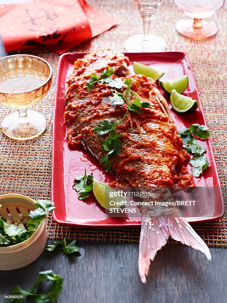 Still life of nyonya snapper with sambal sauce and limes