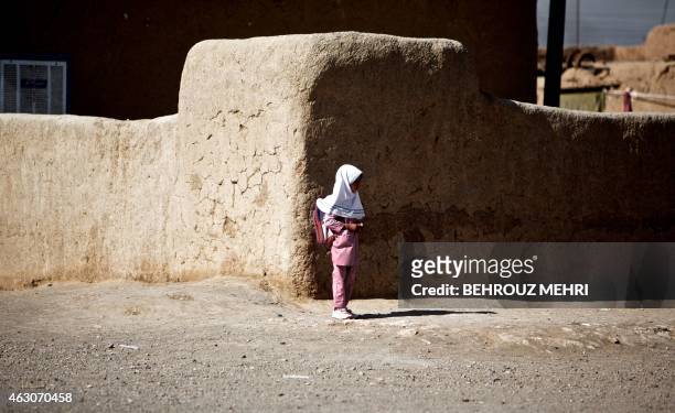 An Afghan schoolgirl stands at a corner on her way home from school at the Shahid Nasseri refugee camp in Taraz Nahid village near the city of Saveh,...