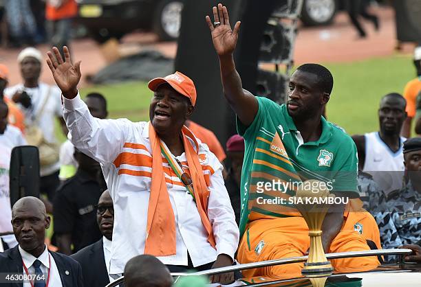 Ivorian President Alassane Ouattara and Ivory Coast's midfielder and captain Yaya Toure wave at the crowd during a welcoming parade in Abidjan on...