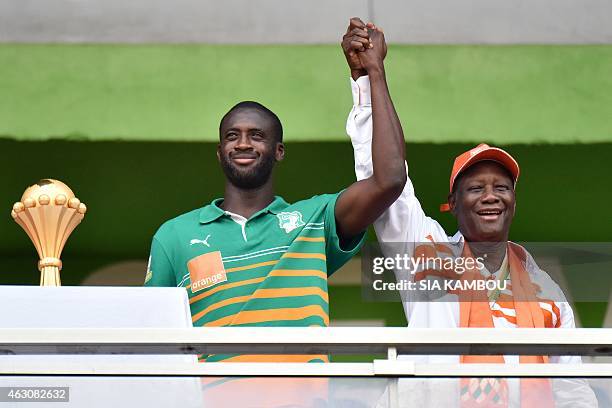 Ivorian President Alassane Ouattara and Ivory Coast's midfielder and captain Yaya Toure raise their arms together next to the 2015 African Cup of...