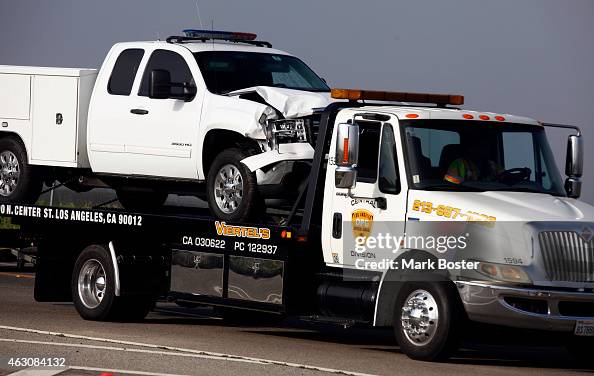 An LAPD bomb squad truck struck is towed away with visible front-end