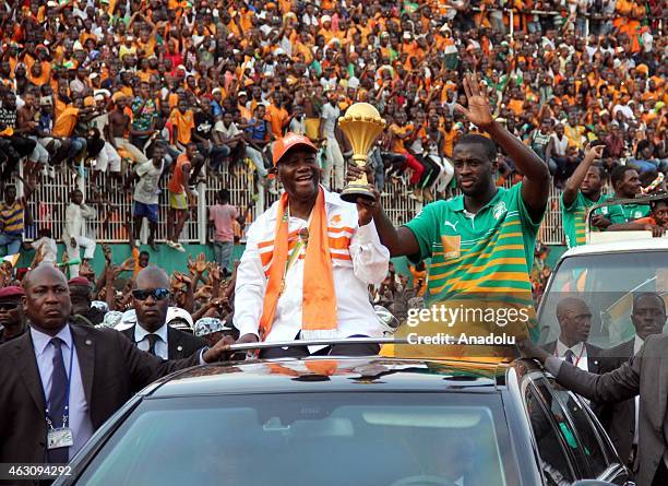 Ivory Coast's President Alassane Ouattara and Ivory Coast's national football team captain Yaya Toure wave to the crowd during a welcoming ceremony...