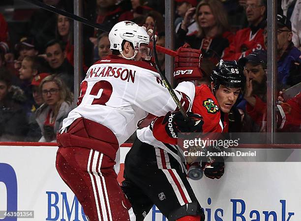 Andrew Shaw of the Chicago Blackhawks is hit in the back by Oliver Ekman-Larsson of the Arizona Coyotes as he passes the puck at the United Center on...