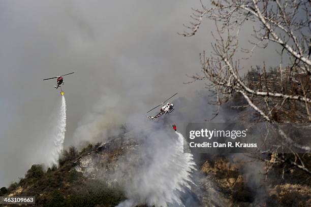 Helicopters work to control wildfires as they burn through hillsides on January 16, 2014 in Azusa, California. Authorities have stated that three...