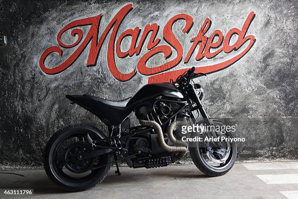 An old motorcycle parked as a display in ManShed Cafe, Sanur. The ManShed cafe in Sanur, Bali is themed on an old style garage and is full of...