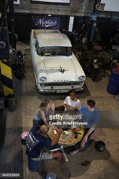 Visitors enjoy hanging out in the garage full of old motorcycles and cars, in ManShed Cafe, Sanur. The ManShed cafe in Sanur, Bali is themed on an...