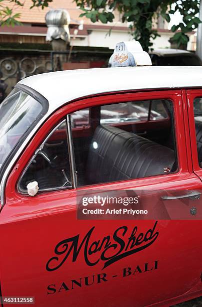 An old car parked outside ManShed Cafe, Sanur. The ManShed cafe in Sanur, Bali is themed on an old style garage and is full of motorcycles and old...