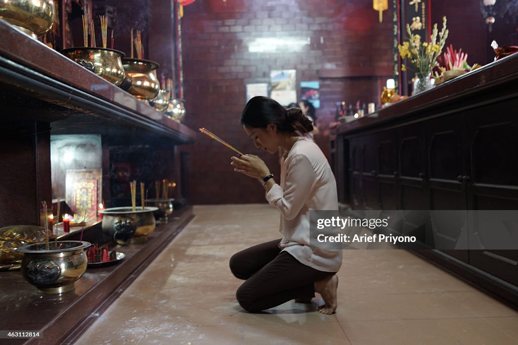 A Chinese woman praying with incense sticks in  the...