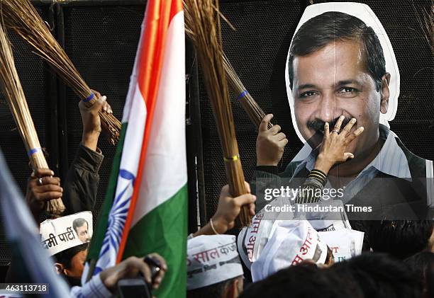 Supporters celebrate holds posters of AAP chief Arvind Kejriwal and party symbol brooms in hand after its victory in Delhi Assembly Election outside...