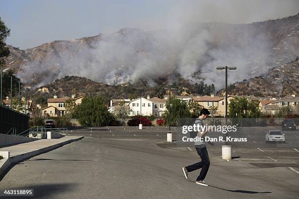 Man walks through the Azusa Pacific University parking lot as wildfires burn in foothills on January 16, 2014 in Azusa, California. Authorities have...