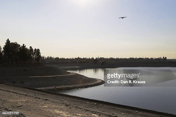 Plane flies over a reservoir as fire emergency services work to control wildfires burning through hillsides on January 16, 2014 in Azusa, California....