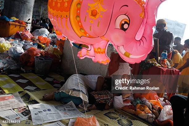 Mother and a child sleep behind an altar during the Thaipusam festival on January 17, 2014 in Kuala Lumpur. Thaipusam is a Hindu festival celebrated...