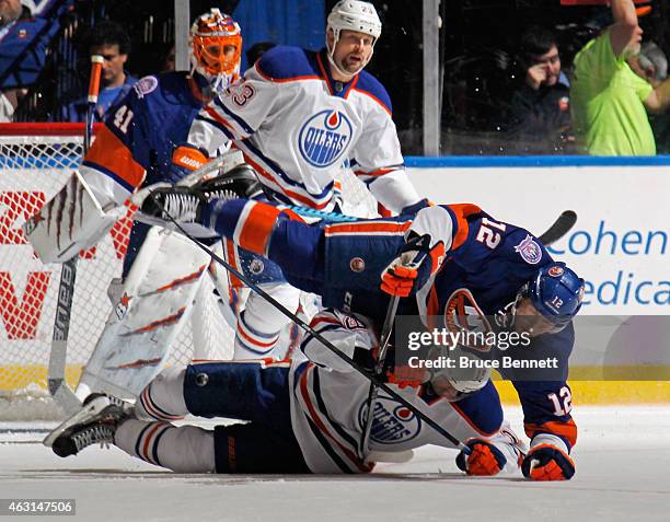 Justin Schultz of the Edmonton Oilers and Josh Bailey of the New York Islanders hit the ice during the second period at the Nassau Veterans Memorial...