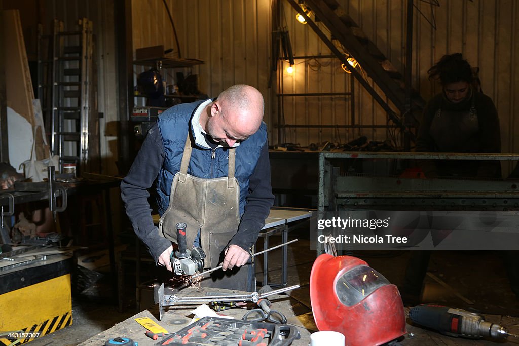 Metal worker and his apprentice working in studio