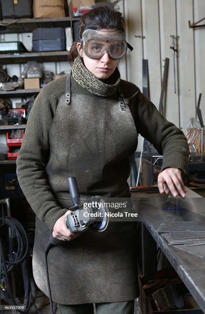 Woman apprentice in metal workshop.