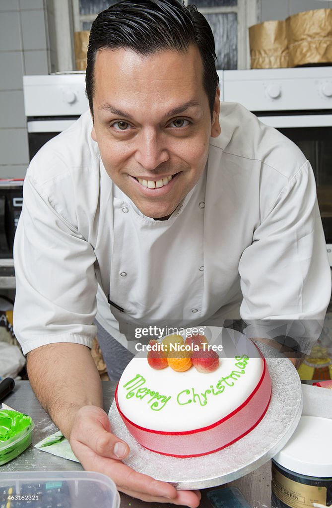 Artisan chef holding decorated christmas cake.