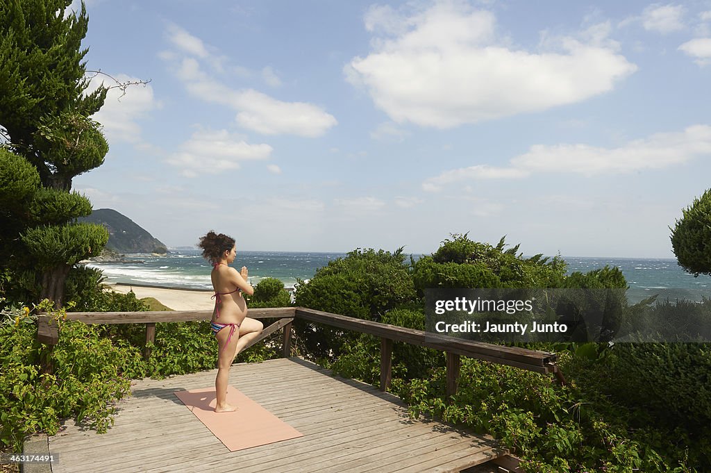 Pregnant woman doing Yoga on the beach side