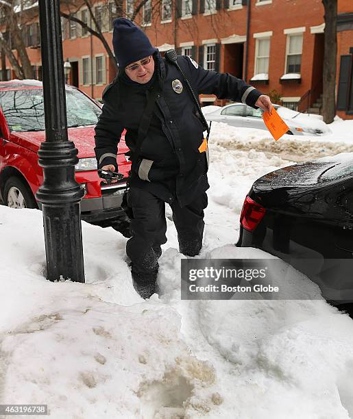 Boston parking enforcement officer Rob Brown struggles through a snow bank on Appleton Street in the South End to ticket a car with an expired...