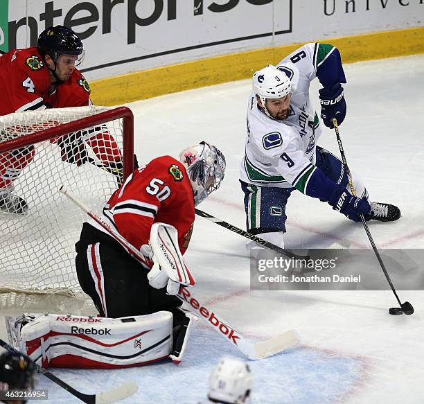 Zack Kassian of the Vancouver Canucks tires to get off a shot from one knee against Corey Crawford of the Chicago Blackhawks and Niklas Hjalmarsson...