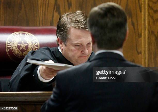 State District Judge Jason Cashon hands back crime scene photosto Erath County District Attorney Alan Nash during the capital murder trial of former...