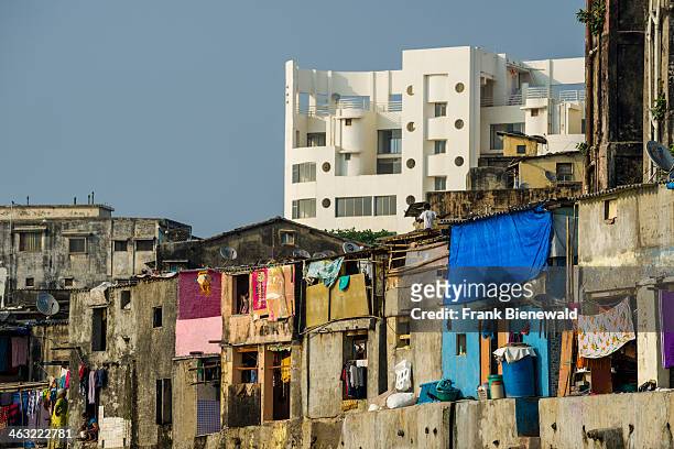 The facades of typical homes of poor working class Indians, similar to the buildings in slum areas, with a modern apartment building behind.