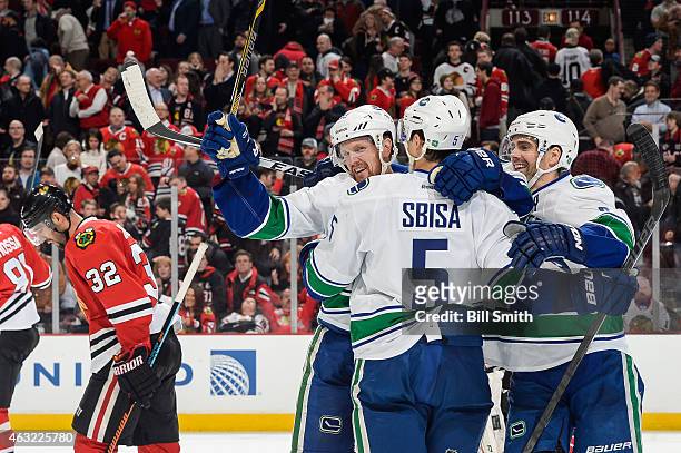 Daniel Sedin of the Vancouver Canucks celebrates with Luca Sbisa and Dan Hamhuis after scoring the game winning goal in overtime against the Chicago...