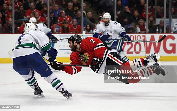 Brent Seabrook of the Chicago Blackhawks goes airbourne as he shoots against past Linden Vey of the Vancouver Canucks at the United Center on...