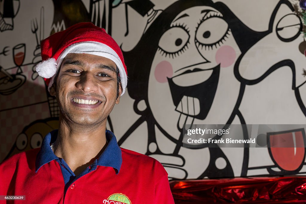 A waiter is wearing a Santa Claus hat at Christmas in a...