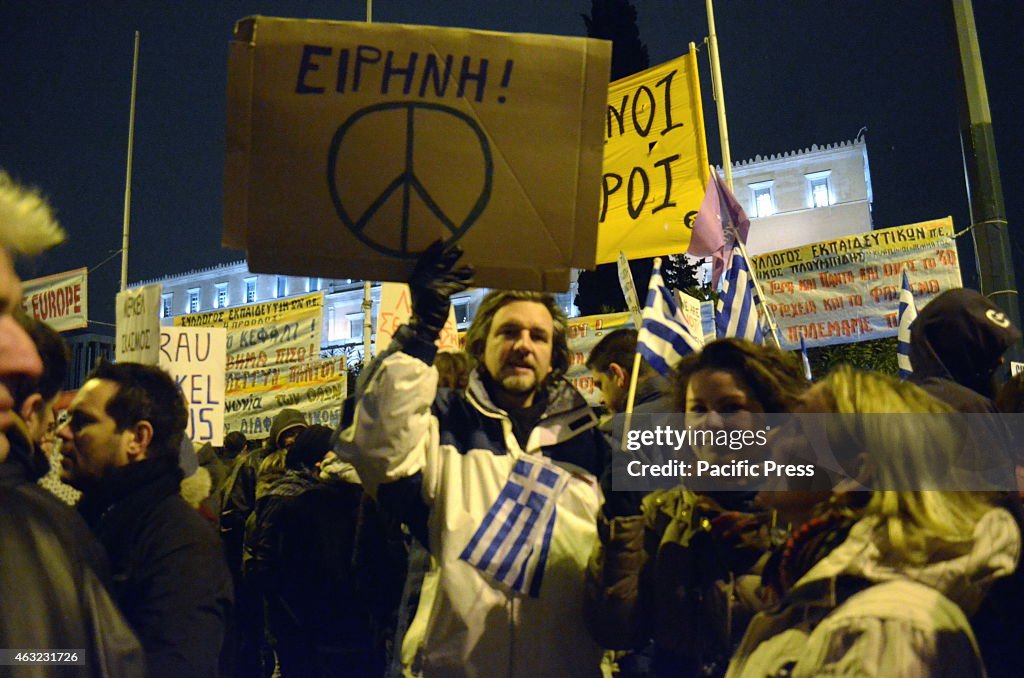 A demonstrator holds a Peace sign and a Greek flag.Huge...