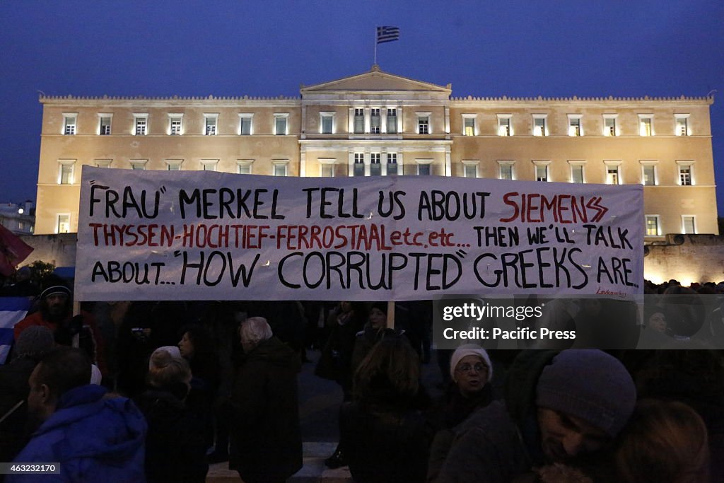 A big banner flies outside the Greek Parliament, reading '...