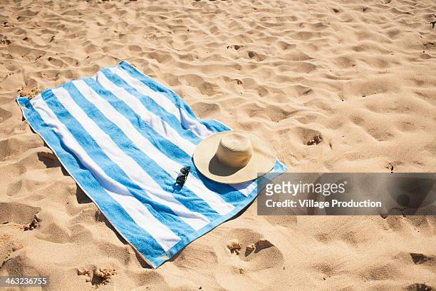 striped beach towel on sand with hat and glasses - telo da mare foto e immagini stock