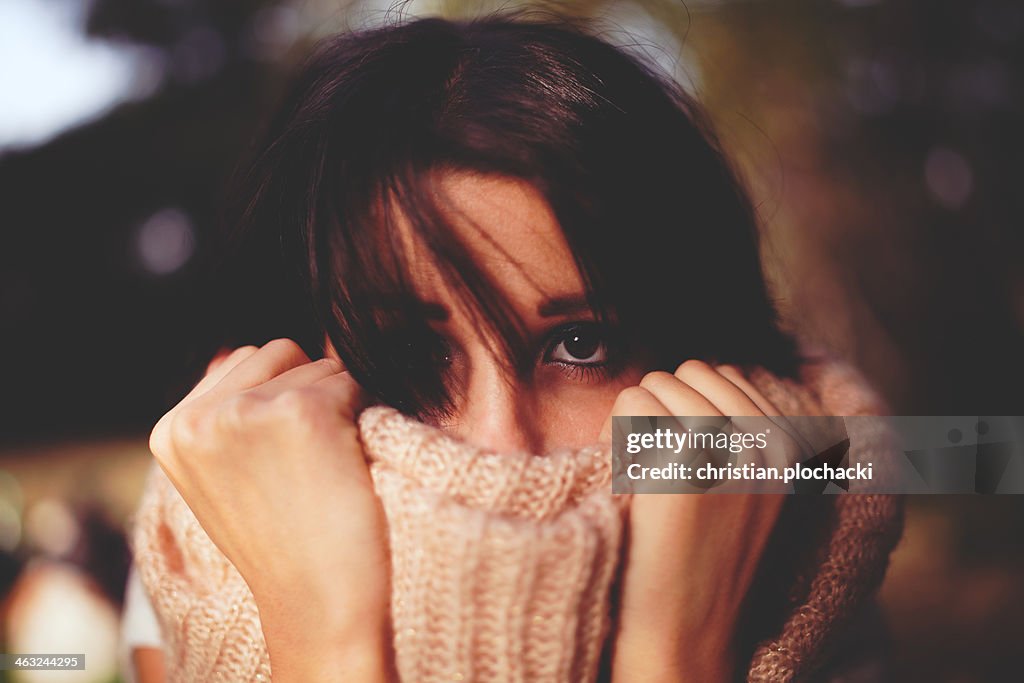 Young woman pulling her muffler into her face