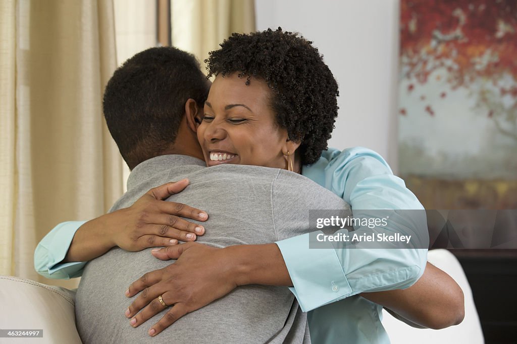 Black couple hugging on sofa