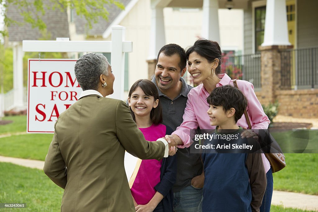 Family shaking hands with Real Estate Agent at new house