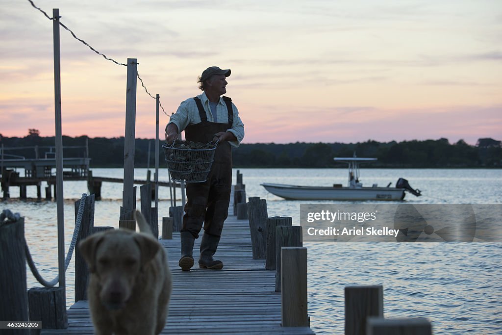 Caucasian fisherman carrying catch on wooden pier